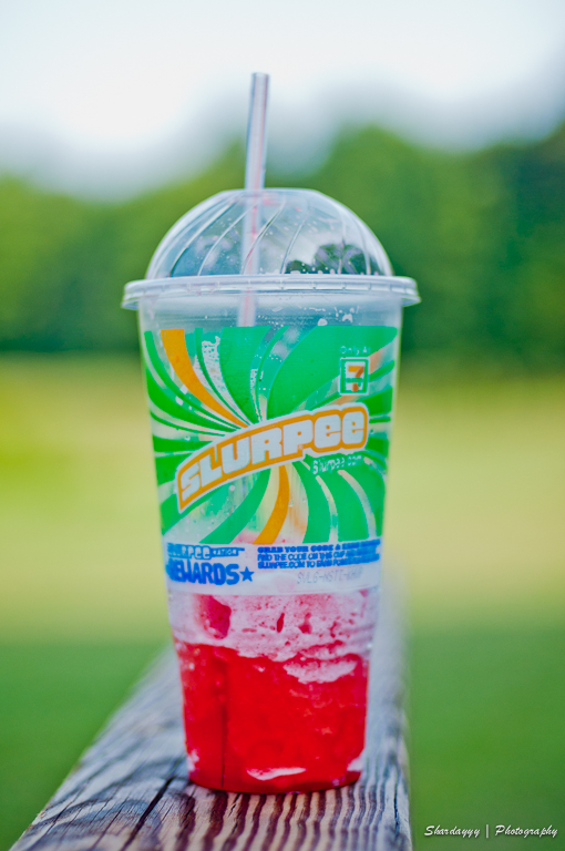 a cold drink with ice and cherry juice in a plastic cup