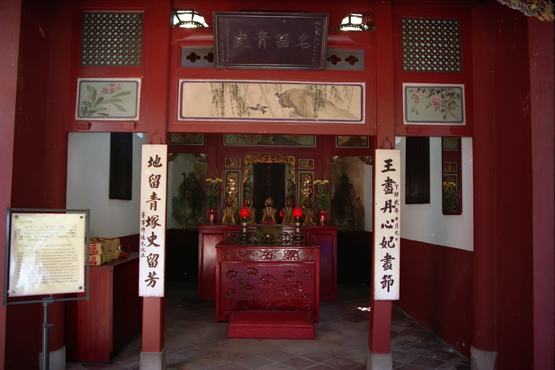 a chinese shrine with a red wall and wooden benches