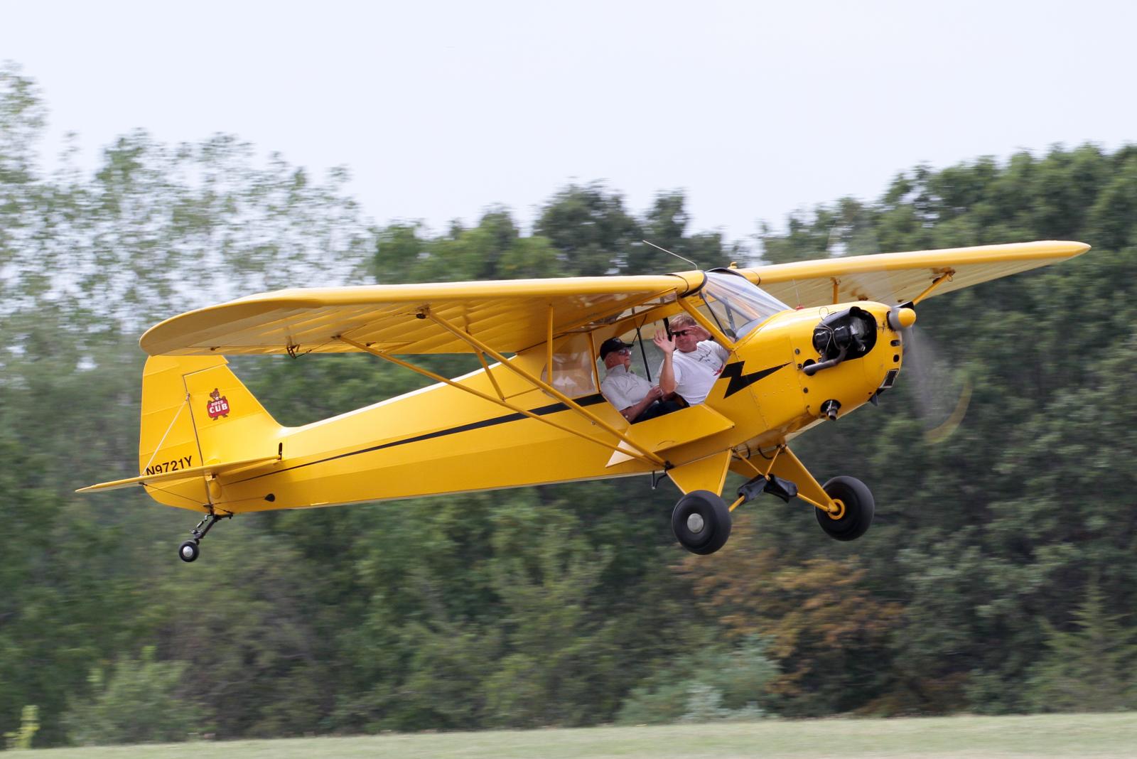 a small yellow plane flying over the forest