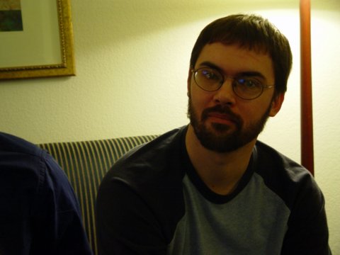 a man with glasses sits next to another man