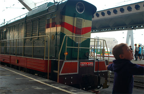 a child standing in front of a train at a station