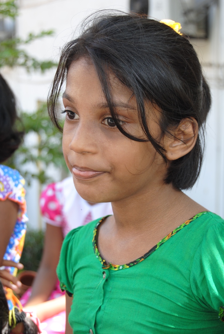 a little girl wearing a green shirt and smiling at the camera