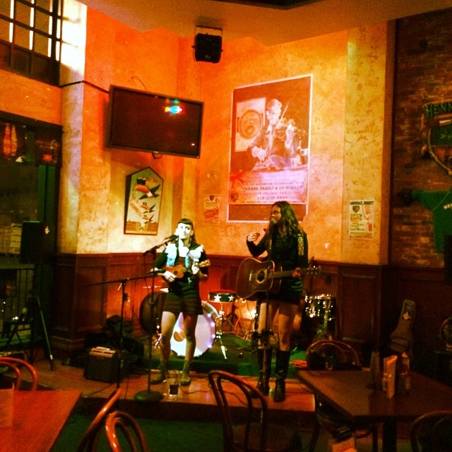 two women singing in the corner of a bar