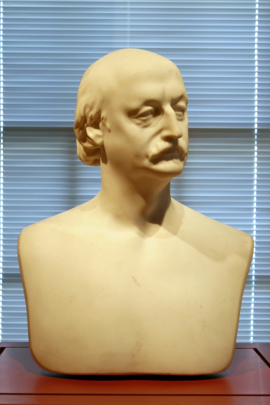 a plaster bust of a man in front of blinds