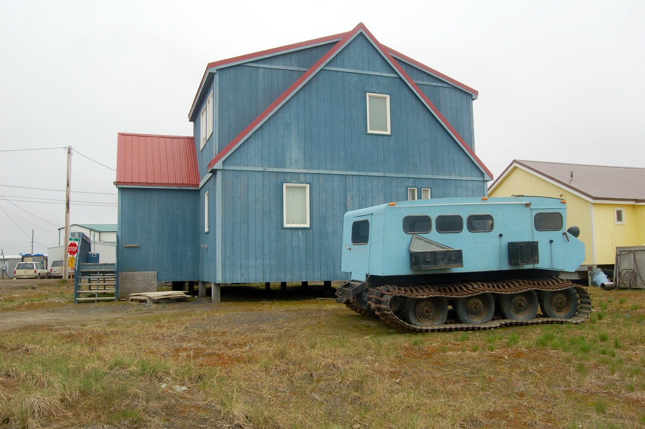 an old, blue fire truck sits in front of a blue building