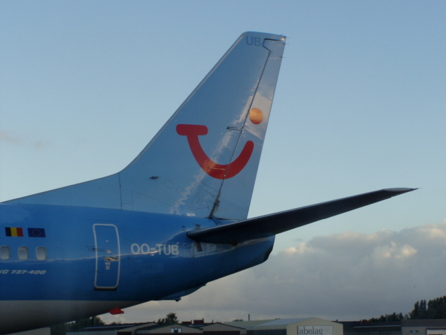 a large blue airplane on the tarmac under a cloudy sky