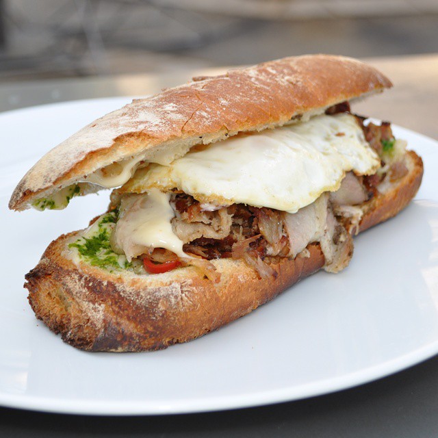 a meat and cheese sub is sitting on a white plate