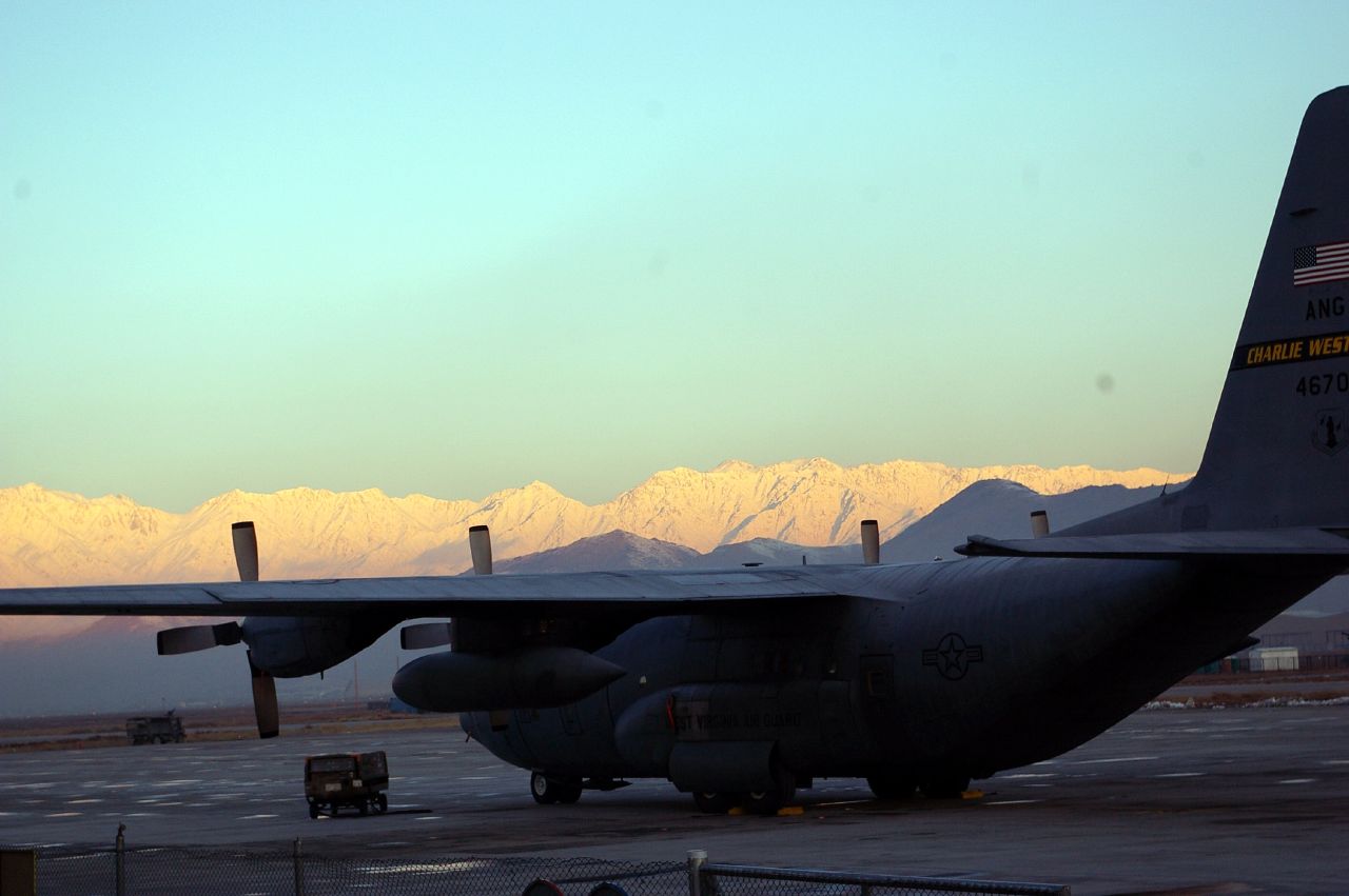 an aircraft parked on the tarmac in front of snow covered mountains