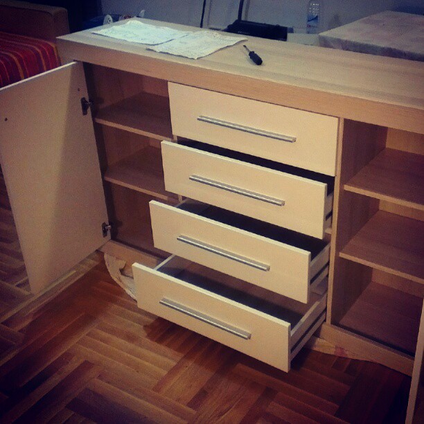 an open drawer under a desk with a notepad on it