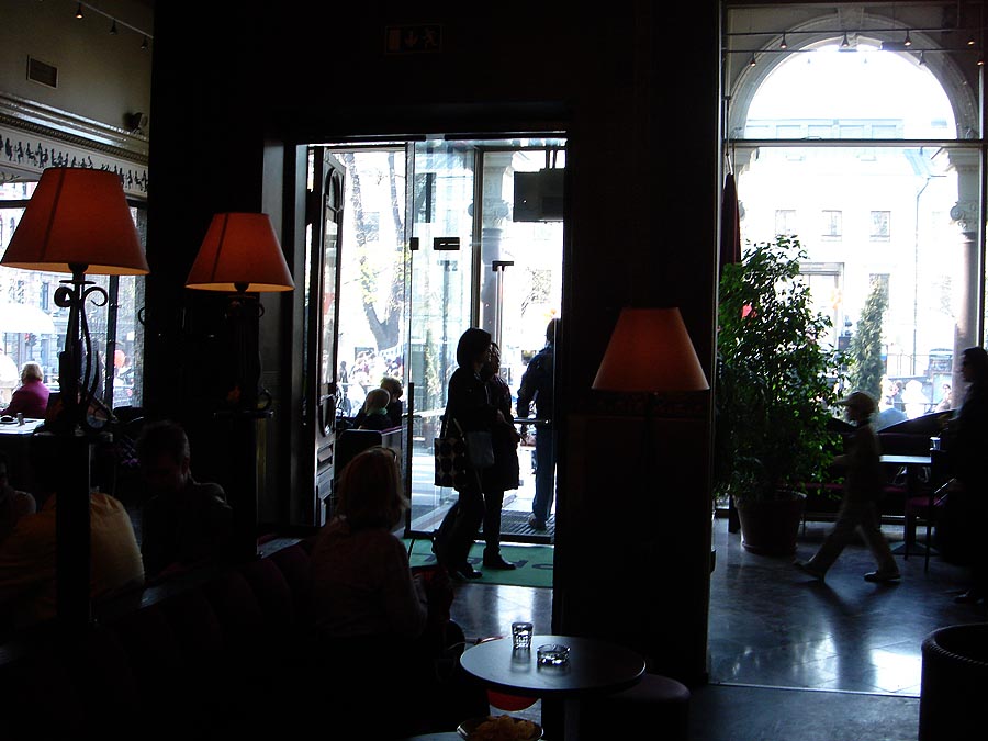 a restaurant with three floor lamps and lots of people in chairs
