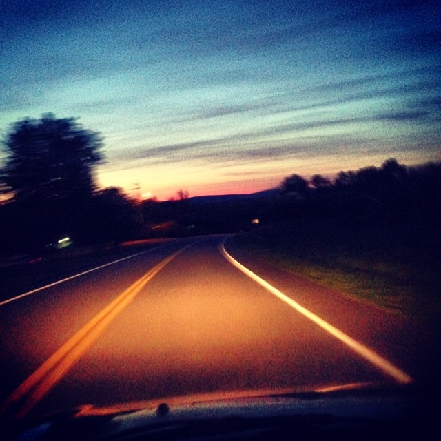 view of road at dusk through windshield of car