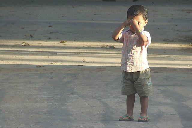 a little boy that is standing up holding a cell phone