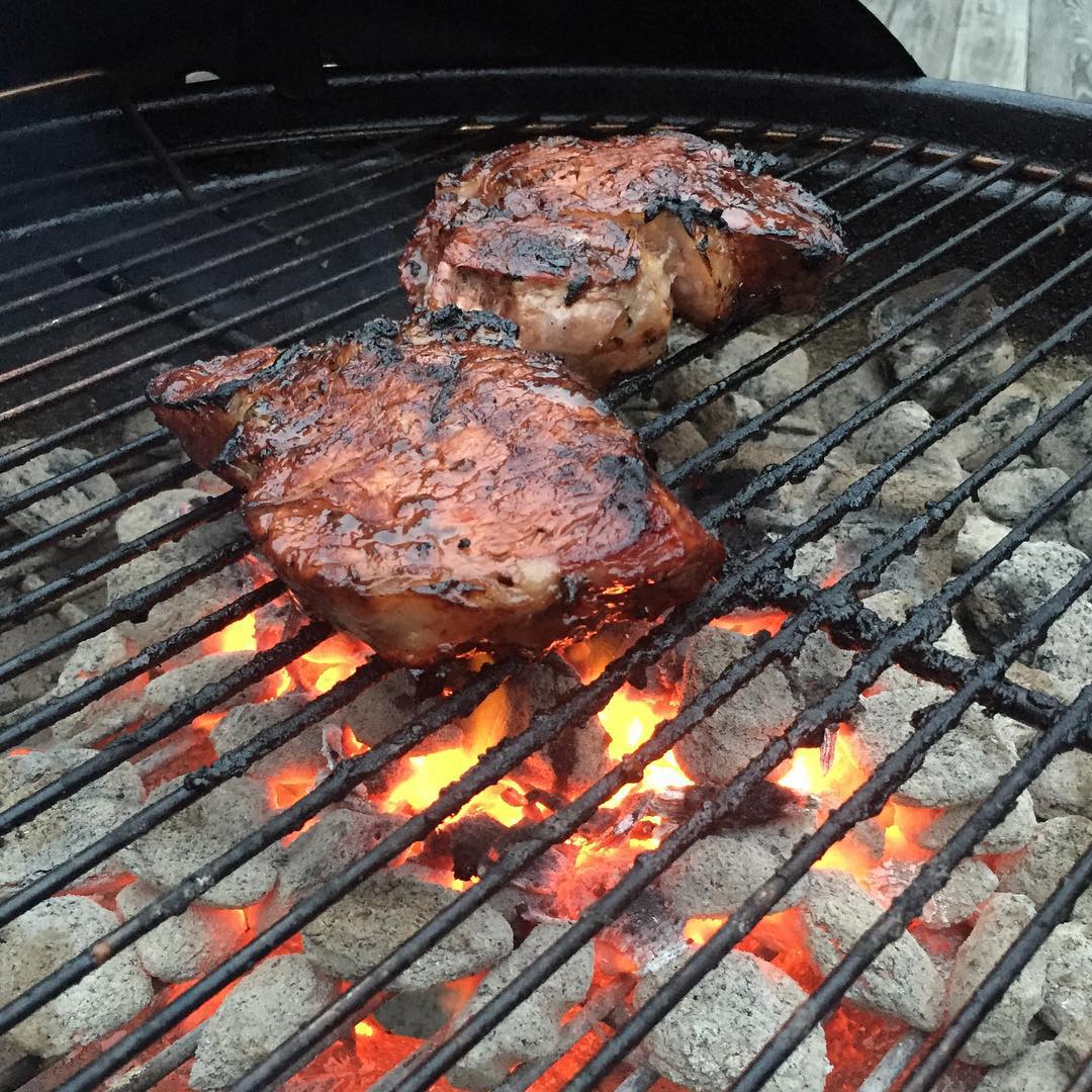 two steaks are cooking on a grill