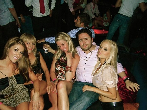 several beautiful blond ladies sitting next to a man