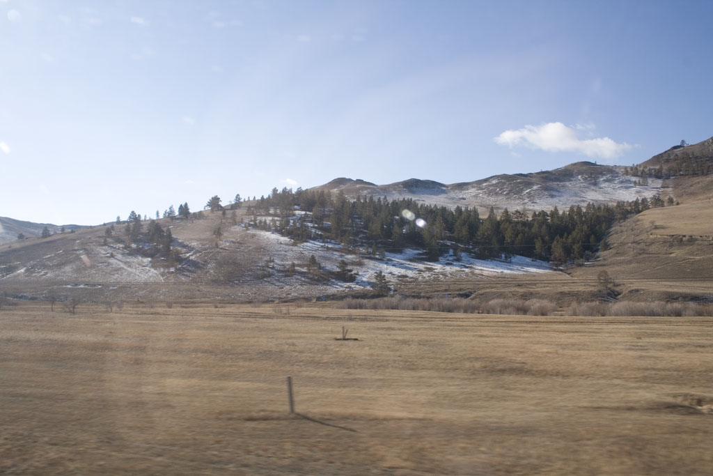 a hill near a fence surrounded by mountains