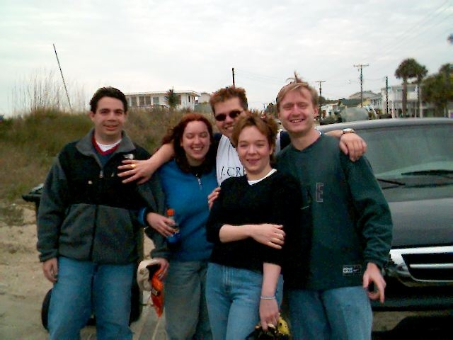 six people posing in front of a truck on the road
