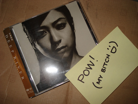 a cd with a woman's face next to a paper sign