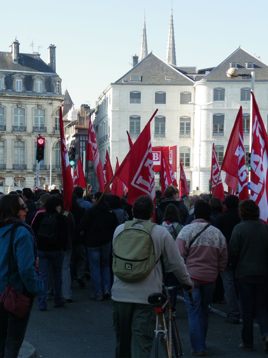 a large crowd of people walking with red flags