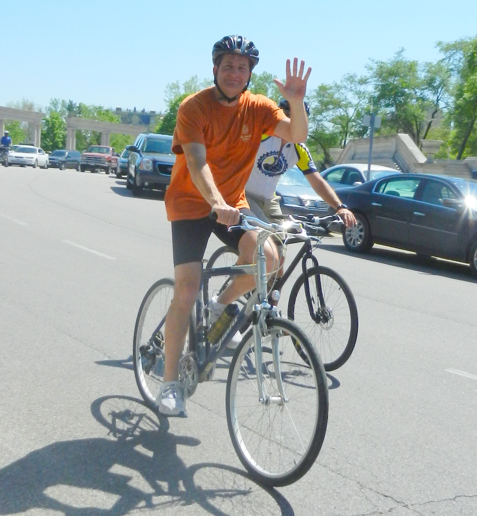 man riding on bike waving to someone in the street