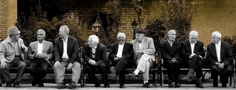 a group of older men sit on top of benches