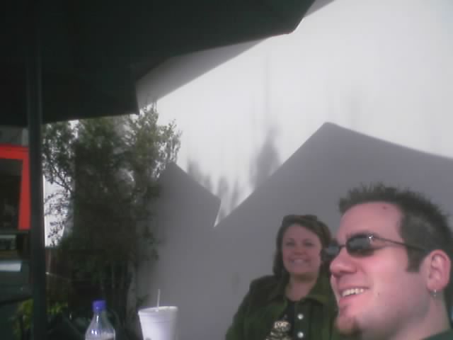 man and woman sitting at a table outside with a bottle of milk