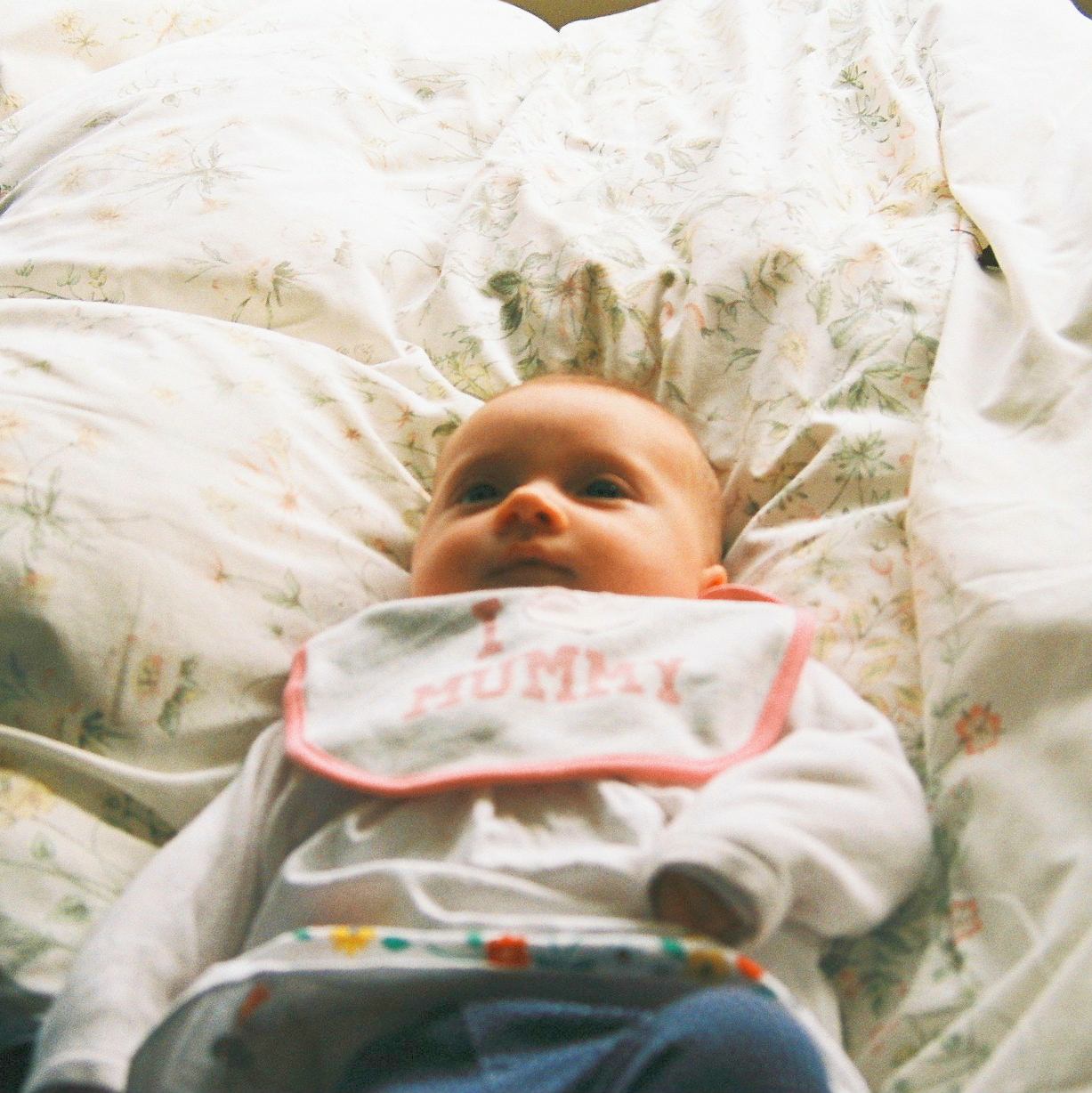 a baby laying in bed with a stuffed animal