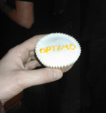 a person holding onto a tiny cupcake that says optma