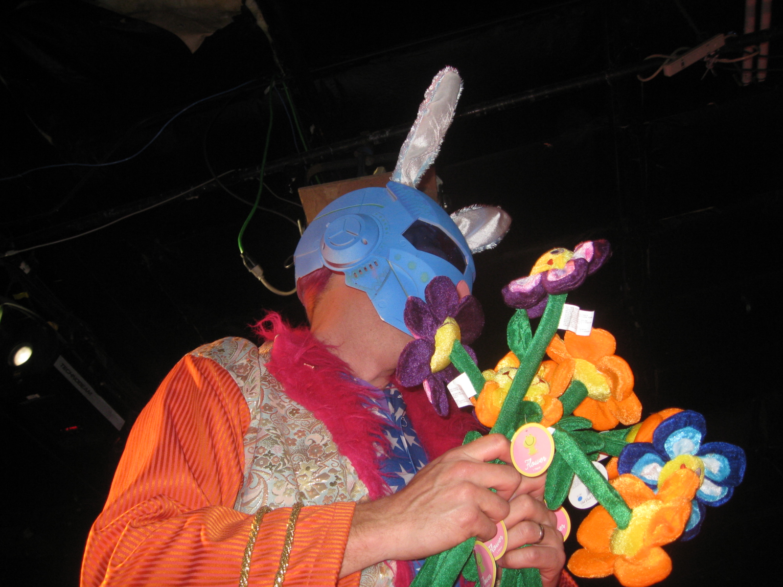 a person in a mask and costume holding a bouquet of flowers