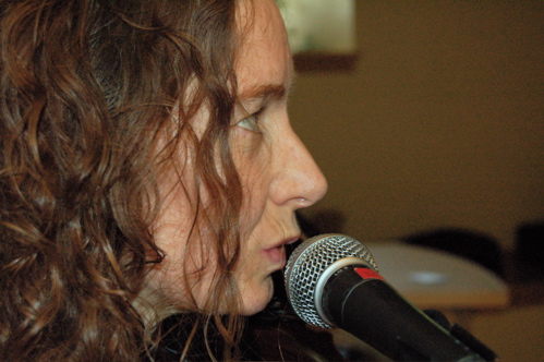 a woman in black shirt talking into microphone