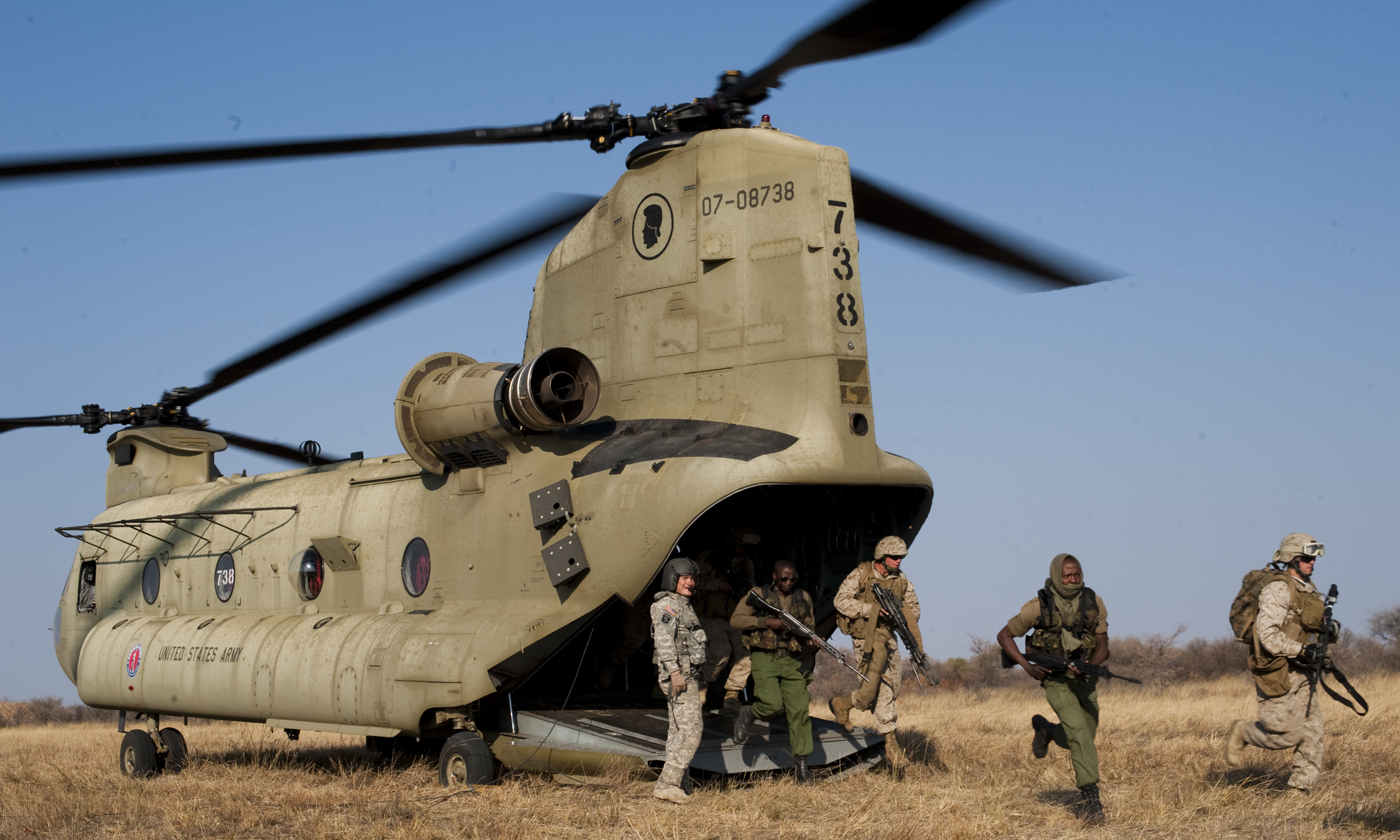 two men and three other men walking away from a helicopter