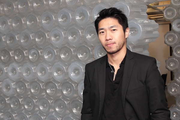 a young asian man standing next to a wall covered with bubble