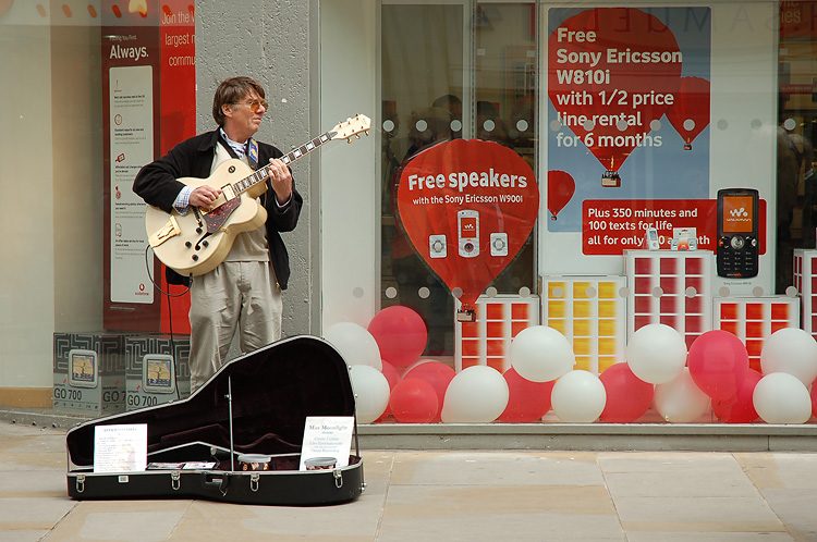 man playing guitar in front of a store window