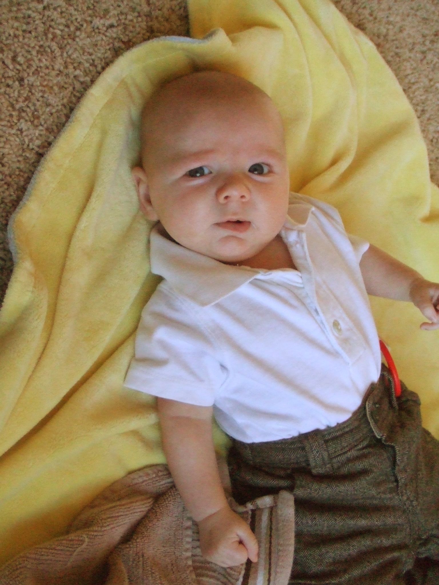 a baby with a shirt and tie laying on carpet
