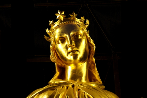 golden statue with crown atop a black background