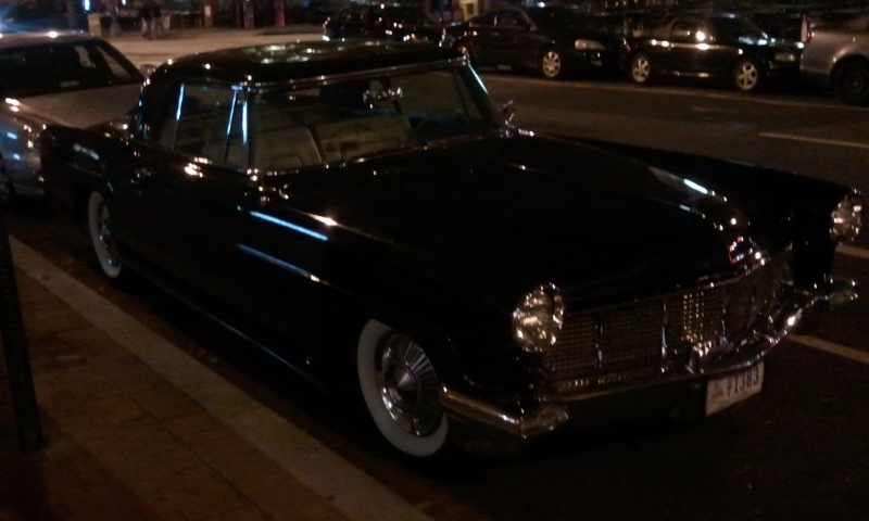 a black convertible car is parked on the sidewalk