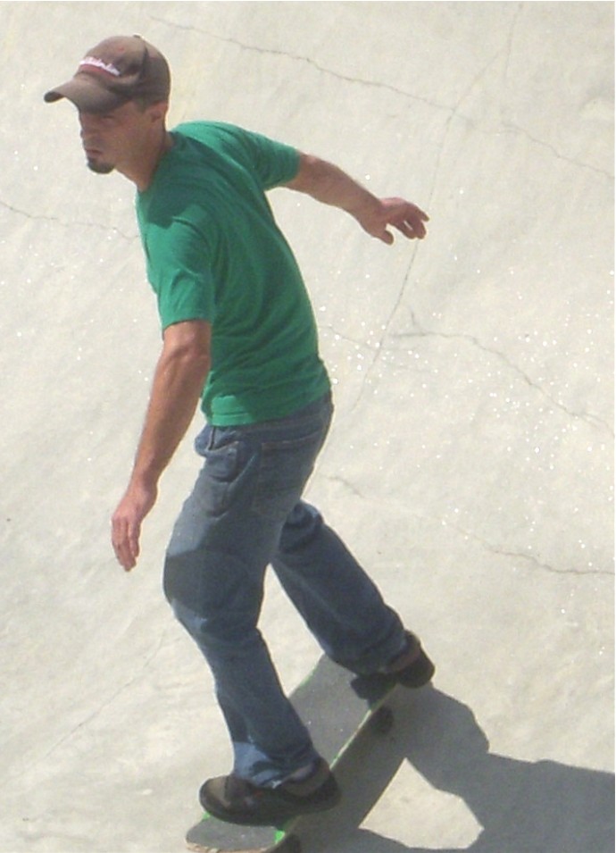 a man in green shirt and hat on a skateboard