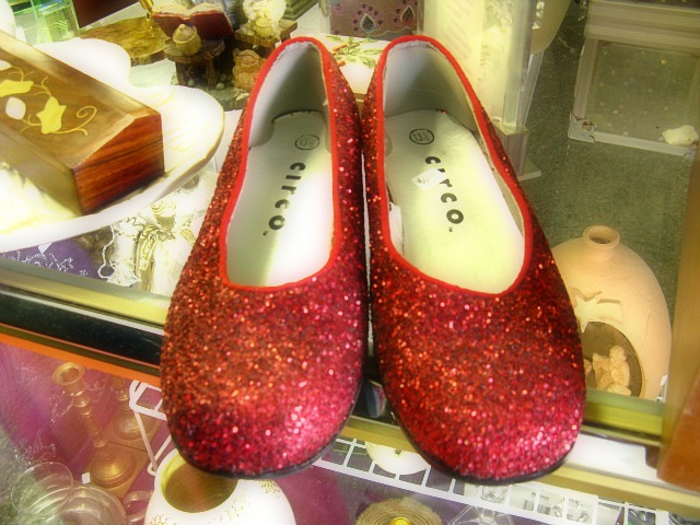 red shoes in a window next to various things on display