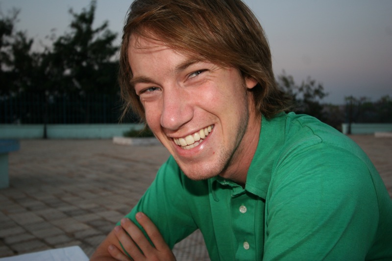 a man in a green shirt is smiling and posing for the camera