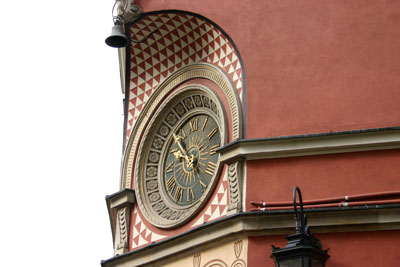 a clock on the corner of a building with a light fixture and some street lamps