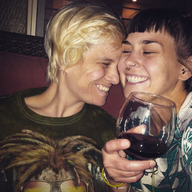 two women, one with nose piercings, sharing a wine glass
