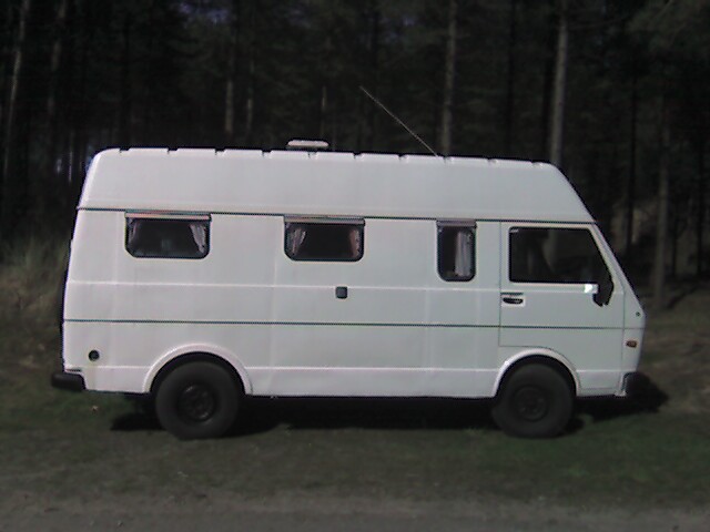 a white motor home parked in a pine forest
