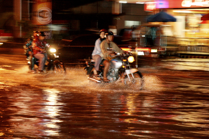 a couple riding motorcycles in the rain