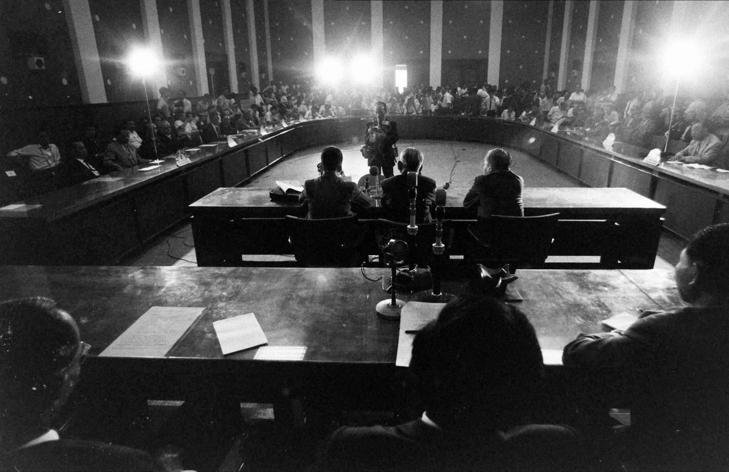 a room full of people sitting down at tables with chairs around them