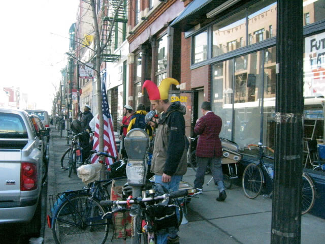 a man on his bike in a street with other bicyclists and people near a parking meter