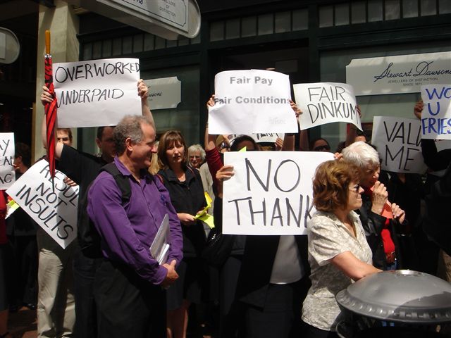 many people holding signs outside of a building