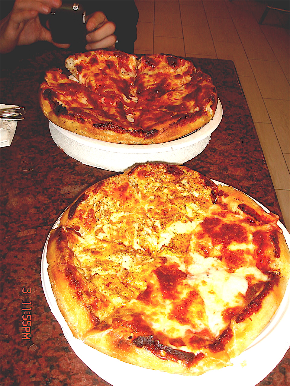 two pizzas sitting next to each other on top of a counter