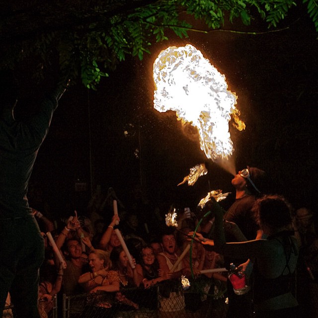 people dancing around a fire show with their arms raised