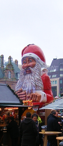 a group of people stand near the giant santa claus