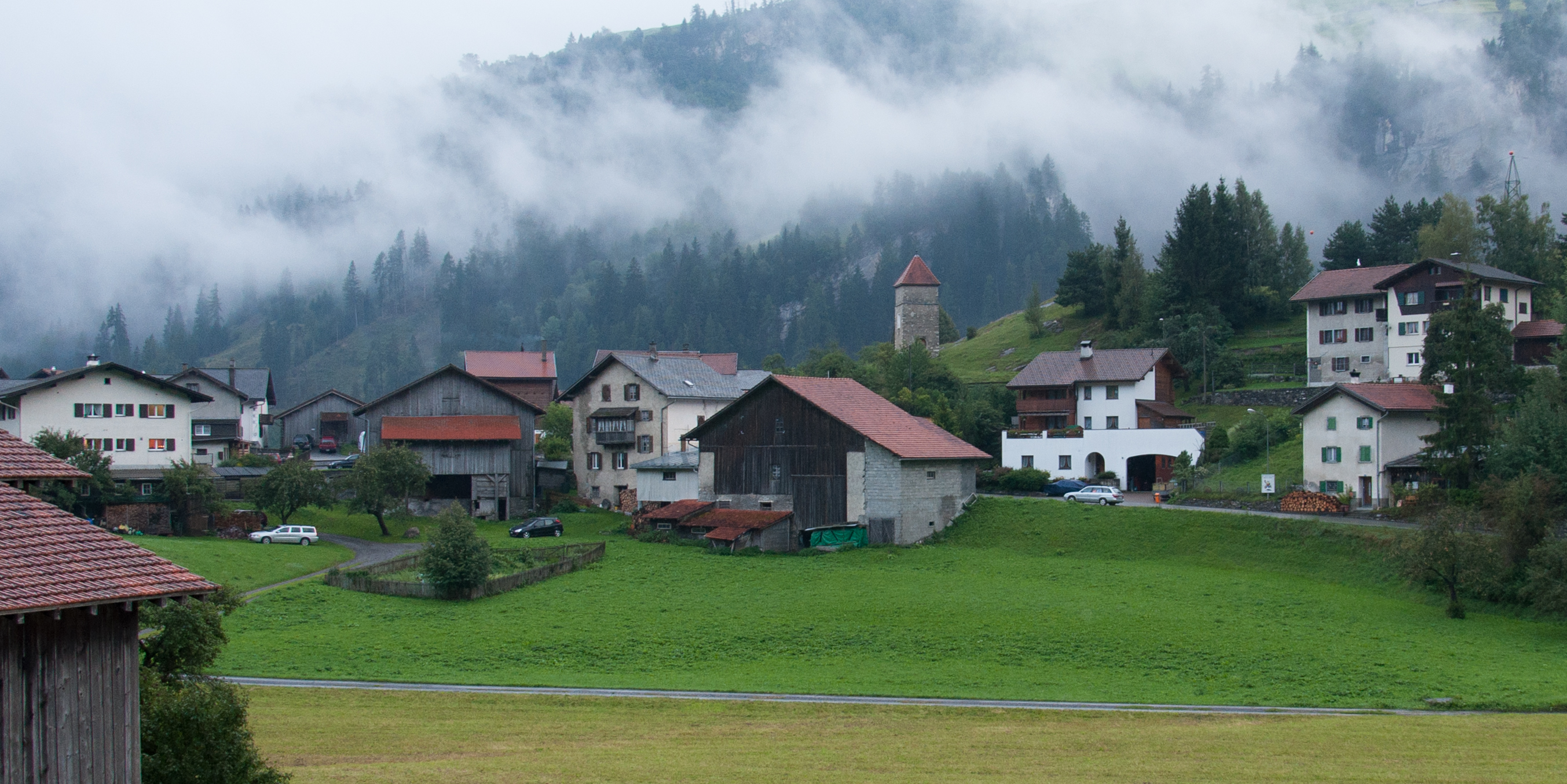 several buildings with windows on a hillside overlooking a grassy area