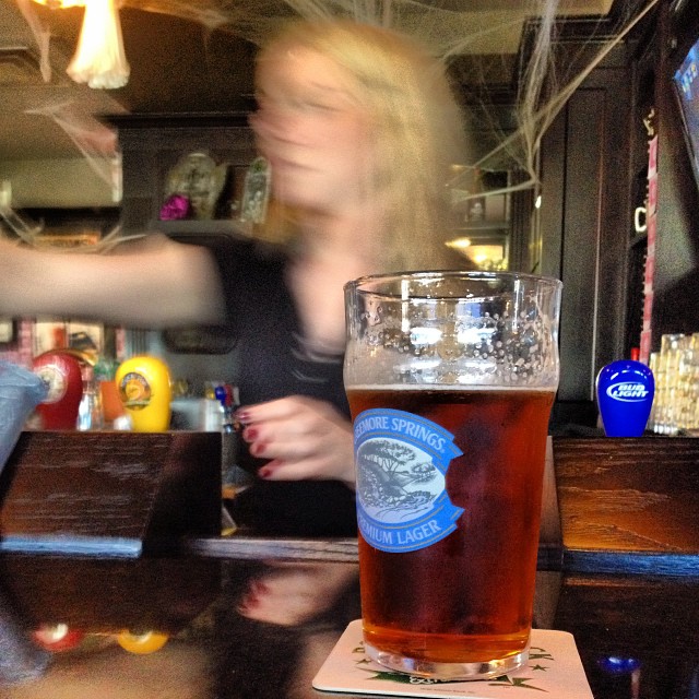 a woman is sitting at the bar with a drink